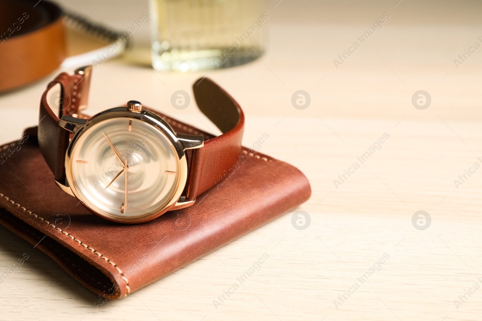 Photo of Luxury wrist watch and wallet on wooden background, closeup. Space for text