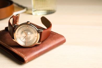 Photo of Luxury wrist watch and wallet on wooden background, closeup. Space for text