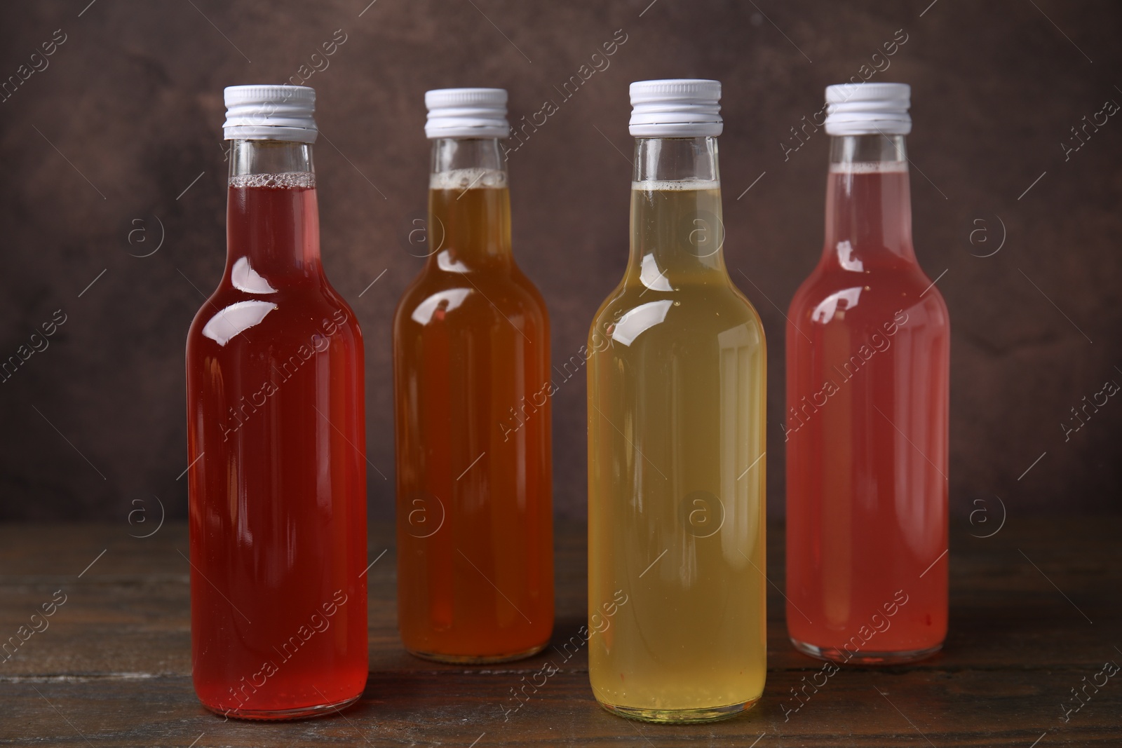 Photo of Delicious kombucha in glass bottles on wooden table