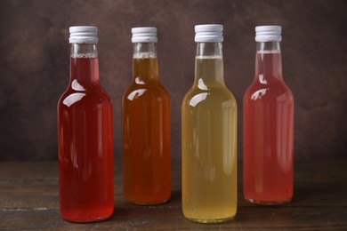 Photo of Delicious kombucha in glass bottles on wooden table