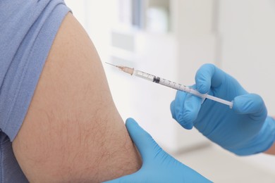 Photo of Doctor giving injection to man in hospital, closeup. Immunization concept