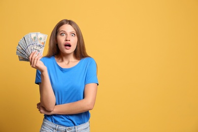 Photo of Portrait of surprised lottery winner with money on yellow background, space for text