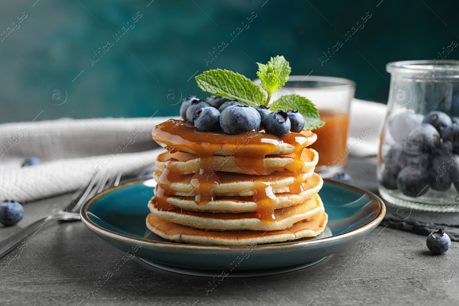 Photo of Delicious pancakes with fresh blueberries and syrup on grey table