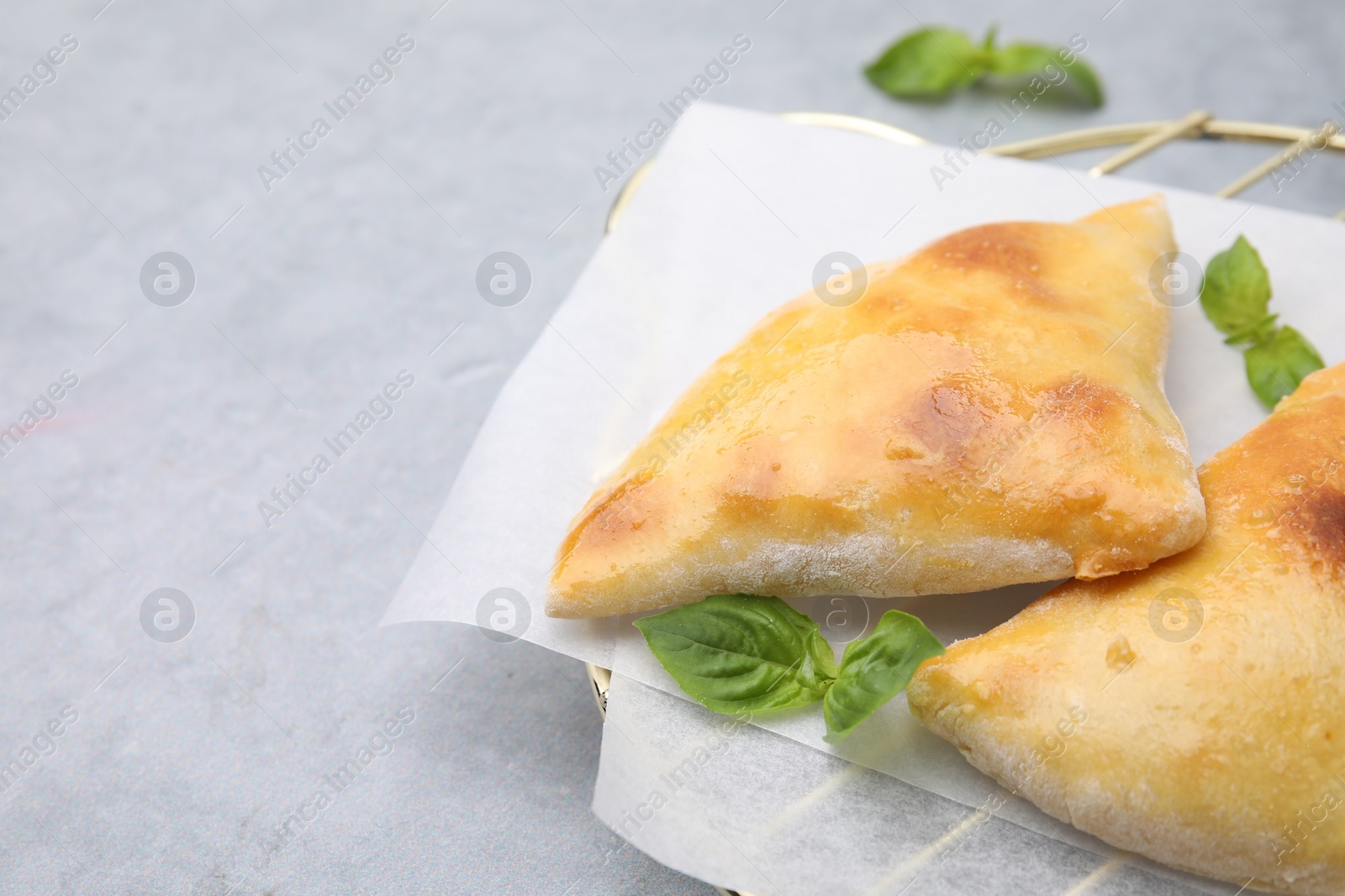 Photo of Delicious samosas and basil on light grey table, space for text