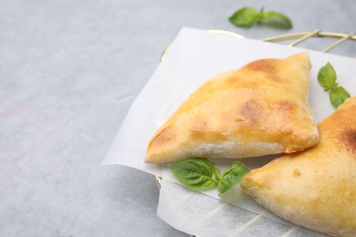 Delicious samosas and basil on light grey table, space for text