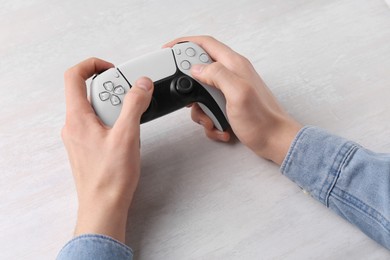 Photo of Man using wireless game controller at white table, closeup