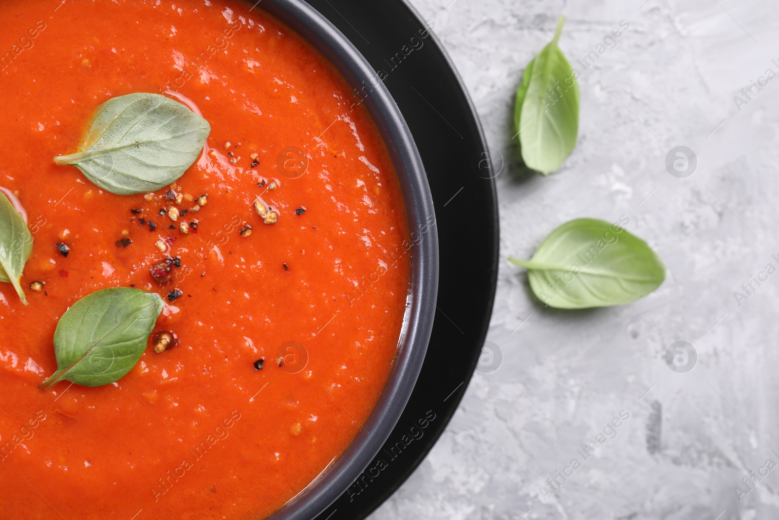 Photo of Delicious tomato cream soup on grey textured table, flat lay. Space for text