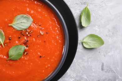 Photo of Delicious tomato cream soup on grey textured table, flat lay. Space for text