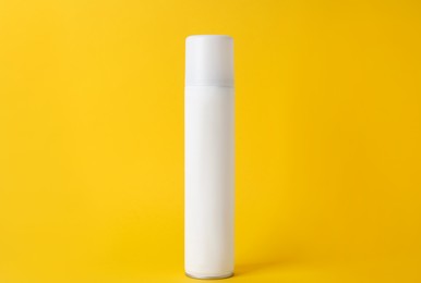 Photo of Bottle of dry shampoo on yellow background
