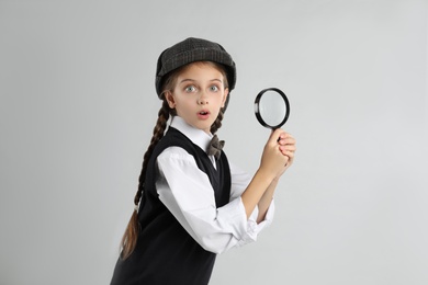 Photo of Cute little detective with magnifying glass on grey background