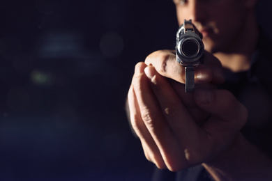 Photo of Professional killer with gun on black background, closeup. Space for text