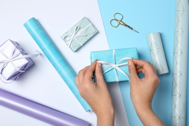 Photo of Woman decorating gift box on color background, top view