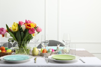 Photo of Easter celebration. Festive table setting with beautiful flowers and painted eggs