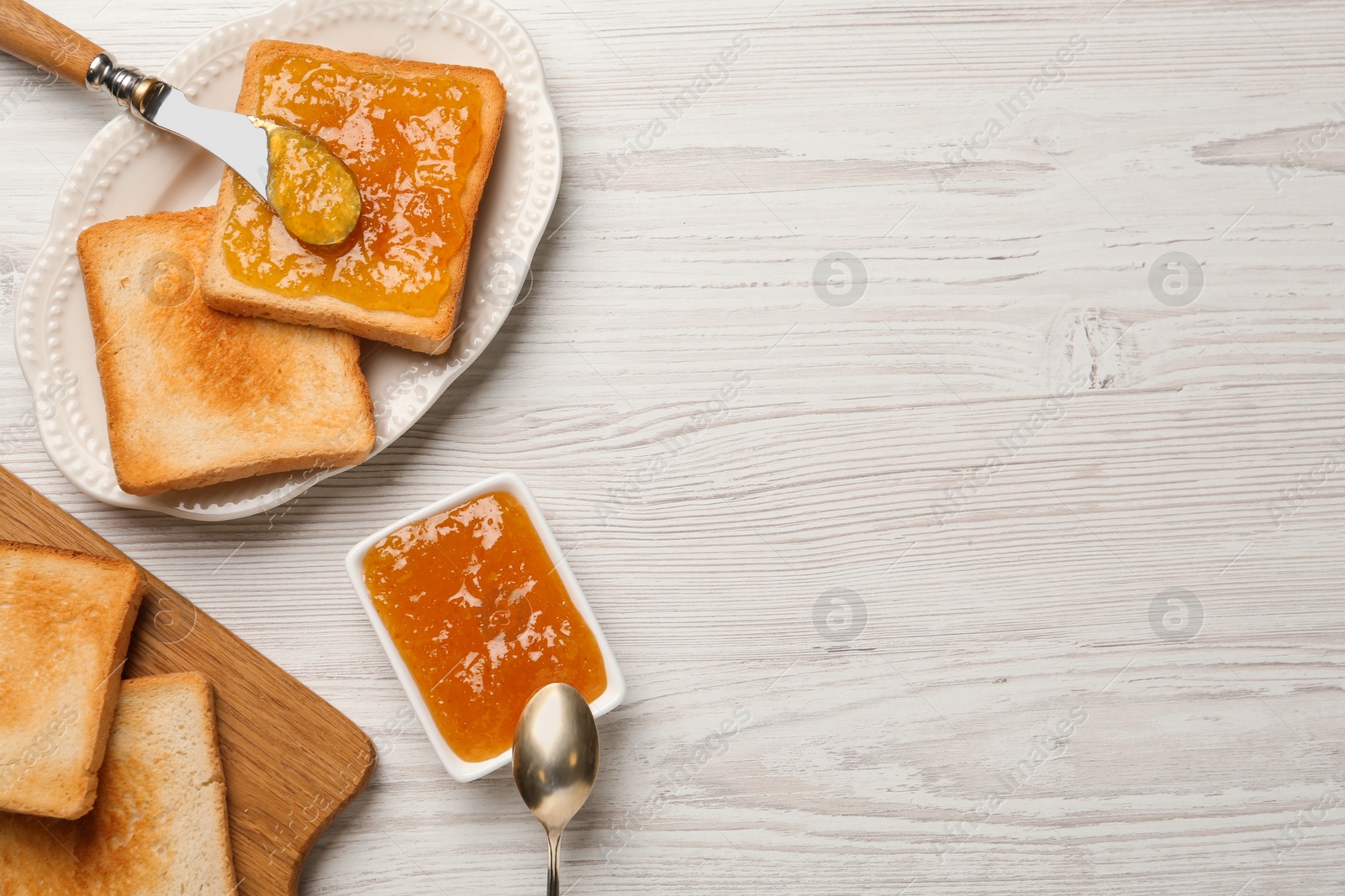 Photo of Toasts and orange jam served on white wooden table, flat lay. Space for text