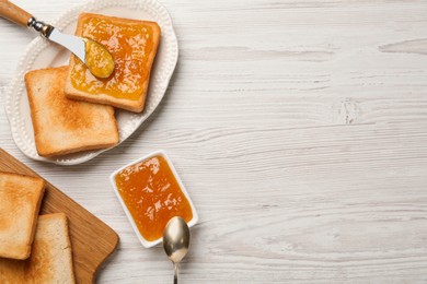 Photo of Toasts and orange jam served on white wooden table, flat lay. Space for text