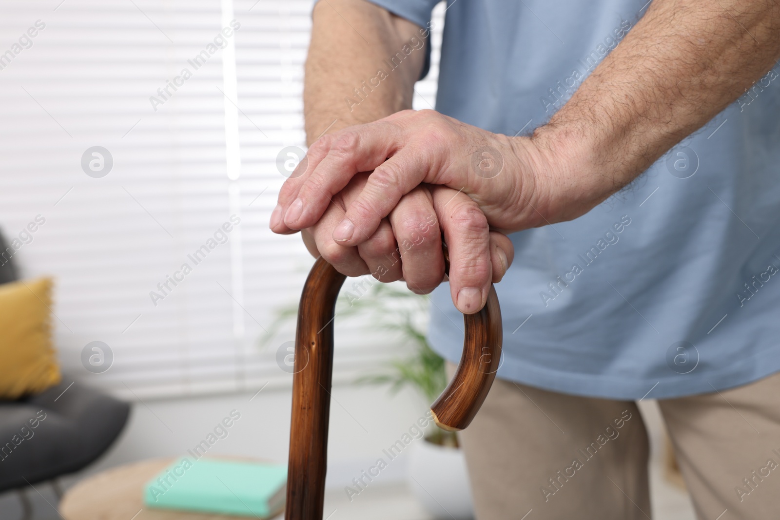 Photo of Senior man with walking cane at home, closeup. Space for text