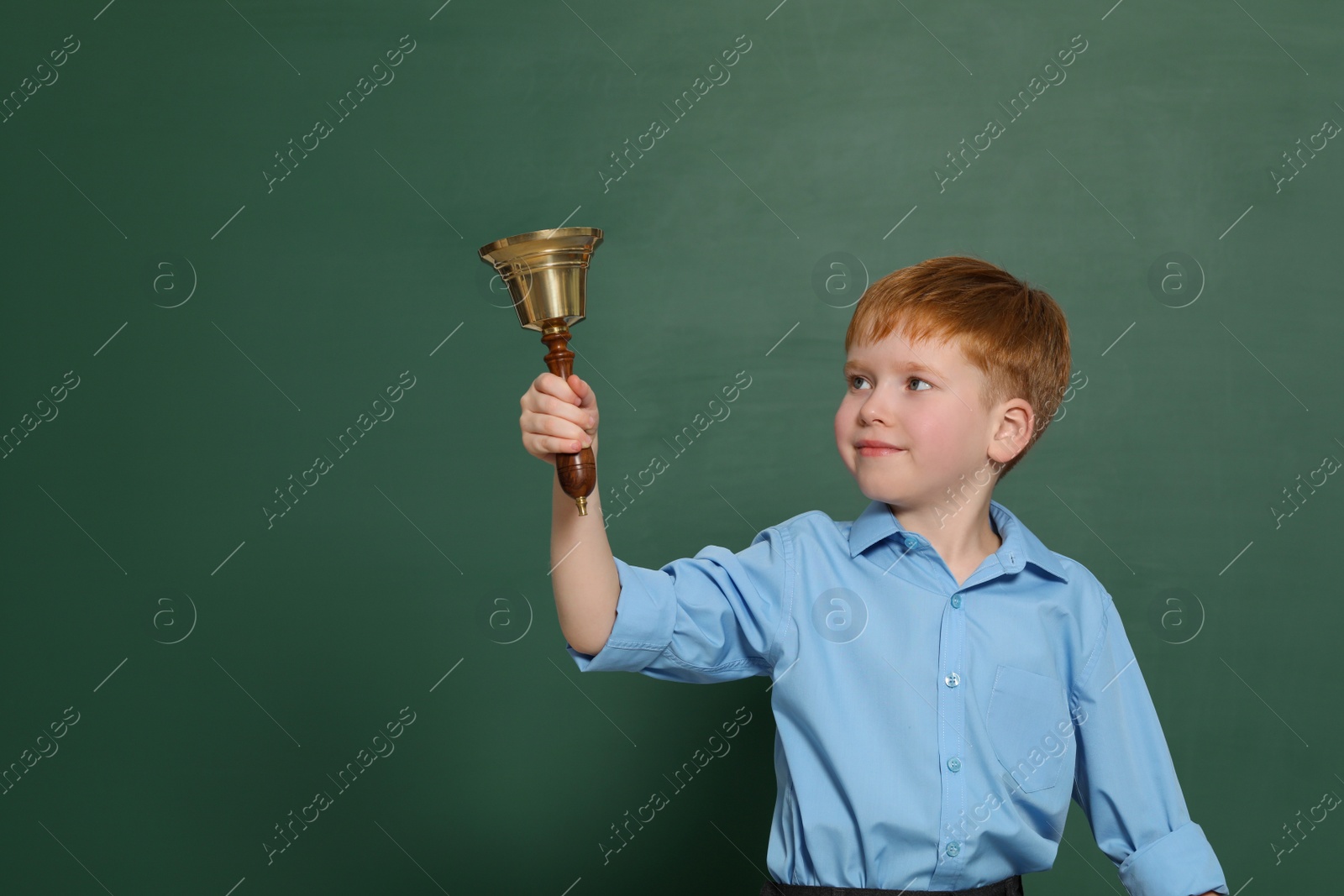 Photo of Pupil with school bell near green chalkboard. Space for text