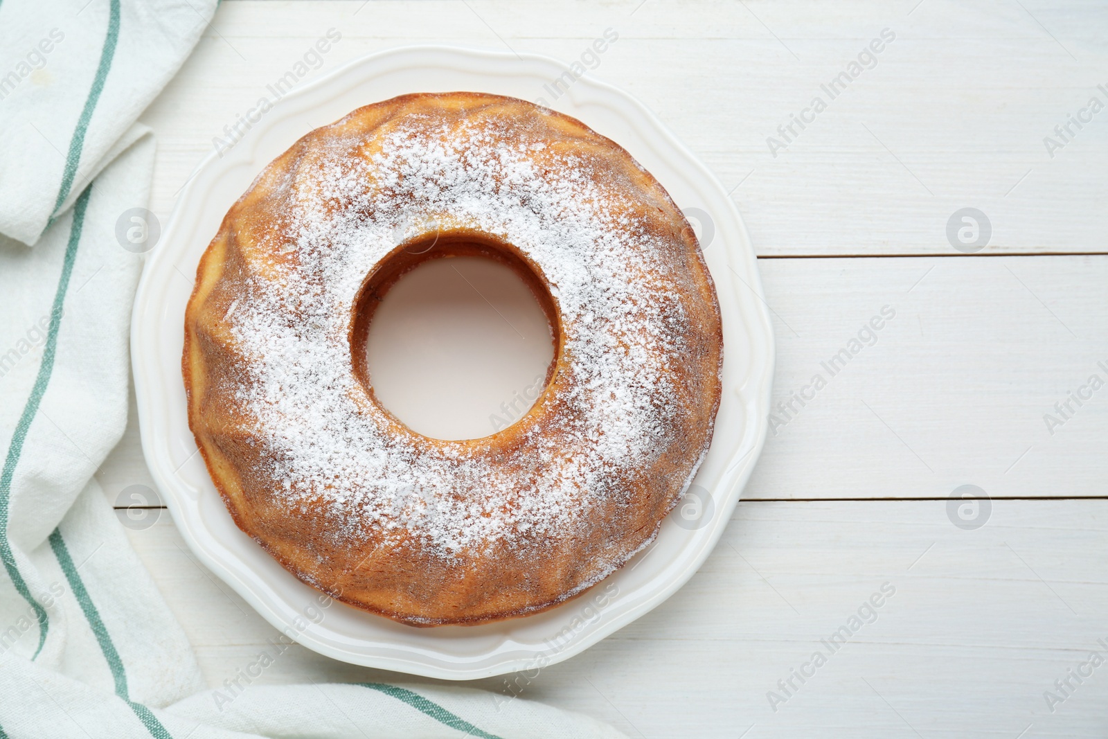 Photo of Homemade yogurt cake with powdered sugar on white wooden table, top view. Space for text