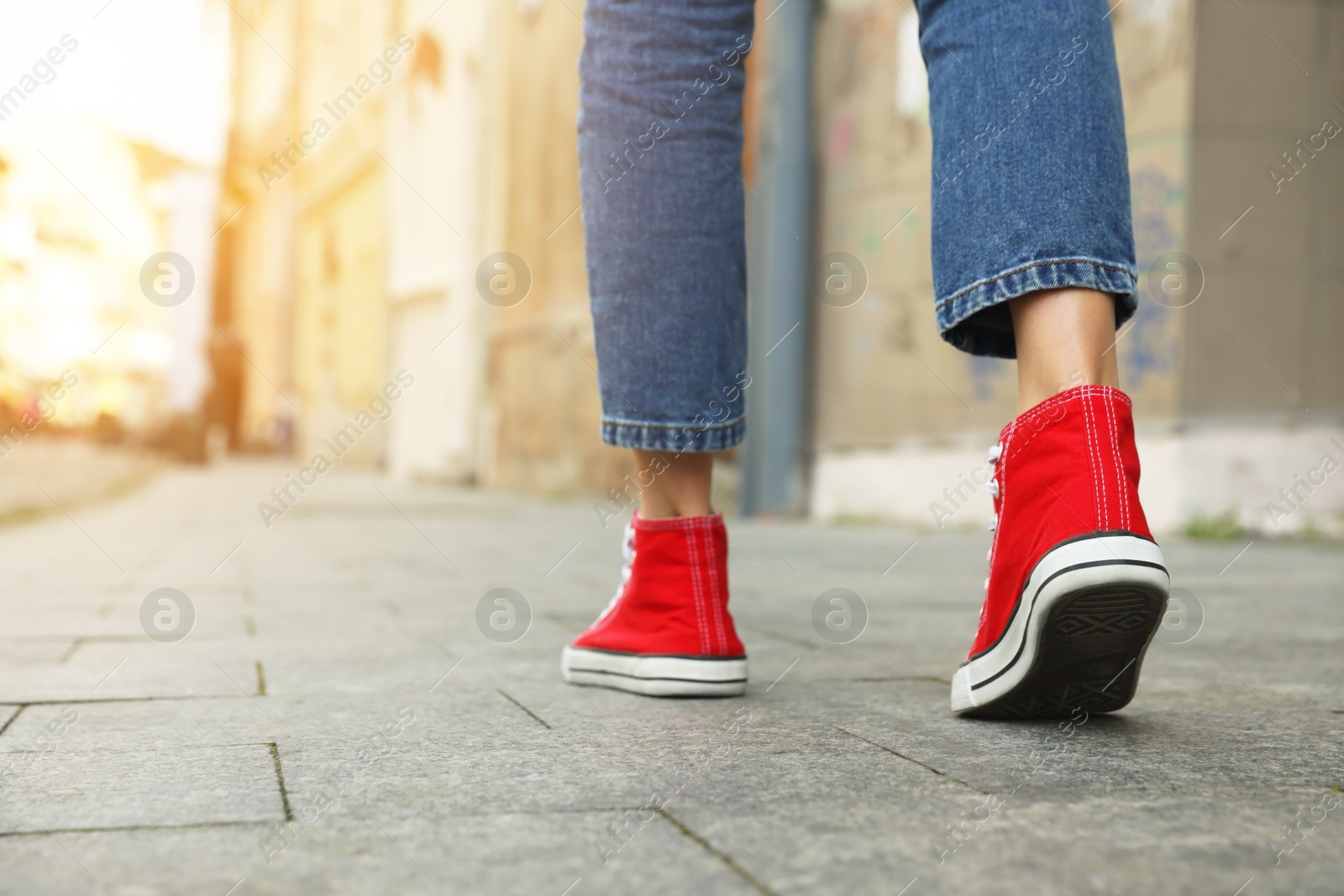 Photo of Woman in stylish sneakers walking on city street, closeup. Space for text