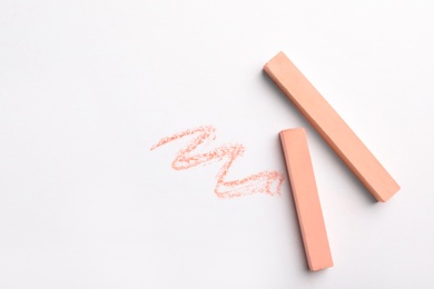 Coral chalk sticks on white background, top view