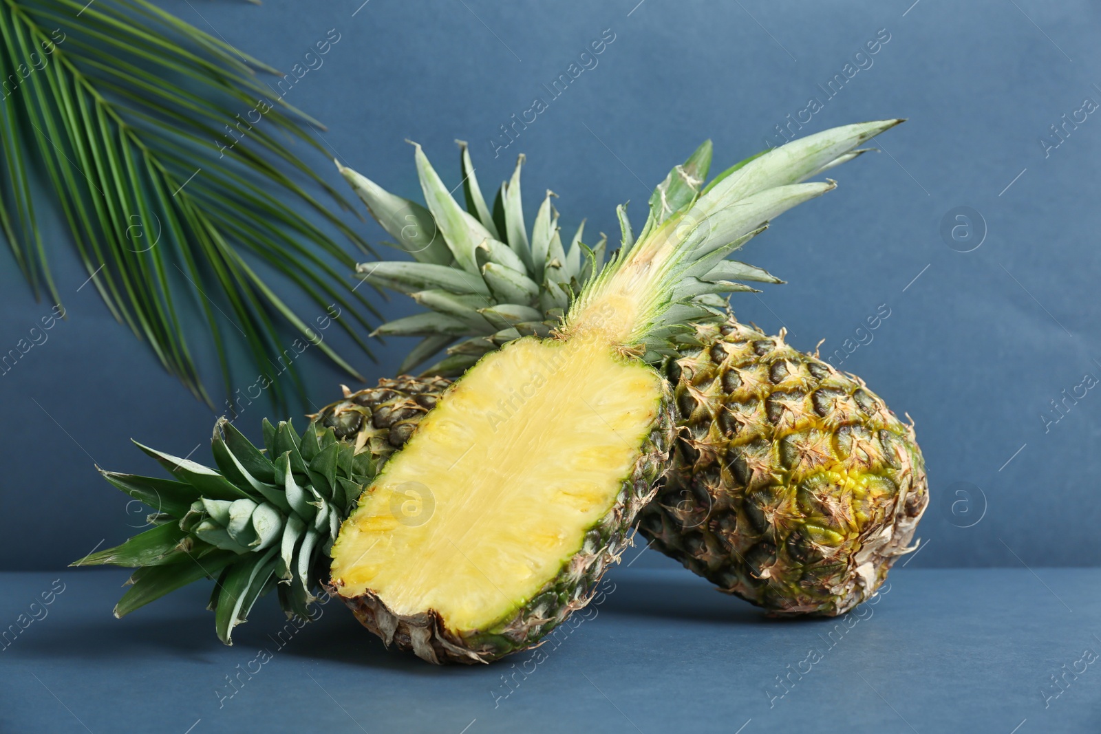 Photo of Fresh pineapples on table against grey wall