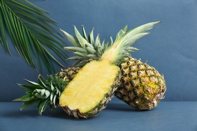 Photo of Fresh pineapples on table against grey wall