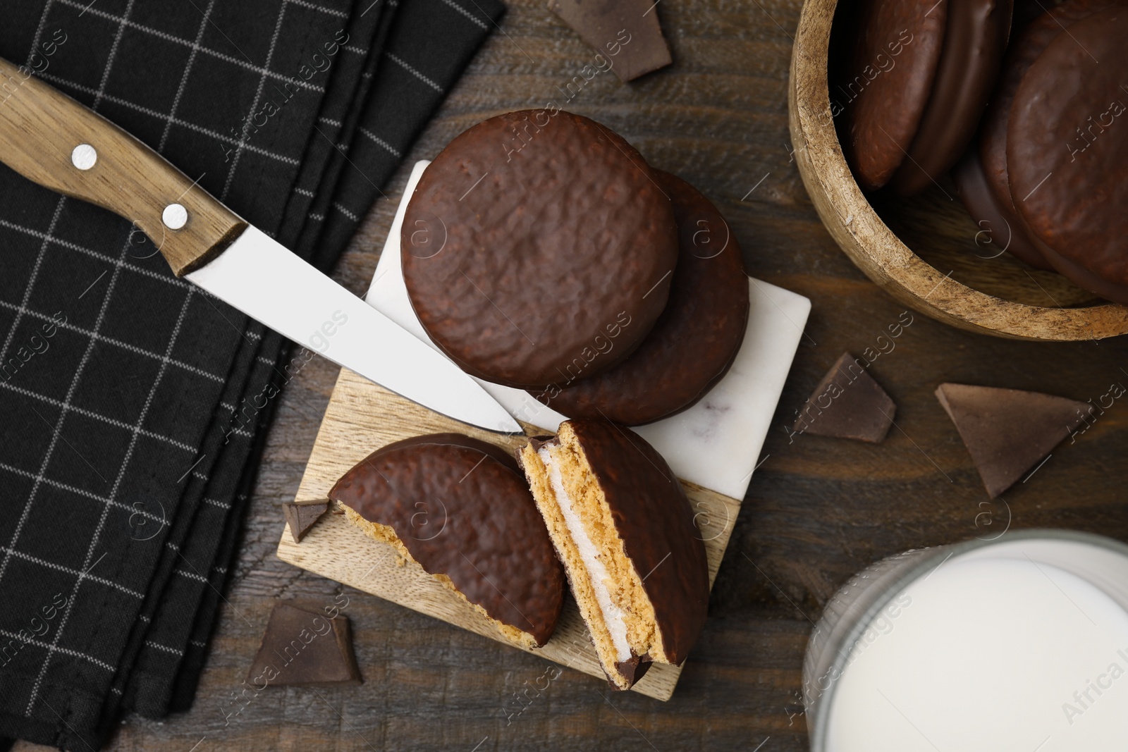 Photo of Tasty choco pies, pieces of chocolate and knife on wooden table, flat lay