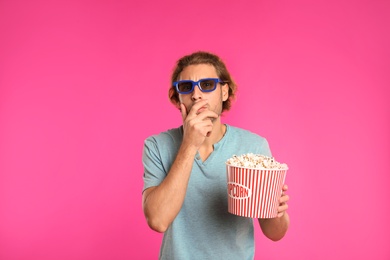 Photo of Emotional man with 3D glasses and popcorn during cinema show on color background