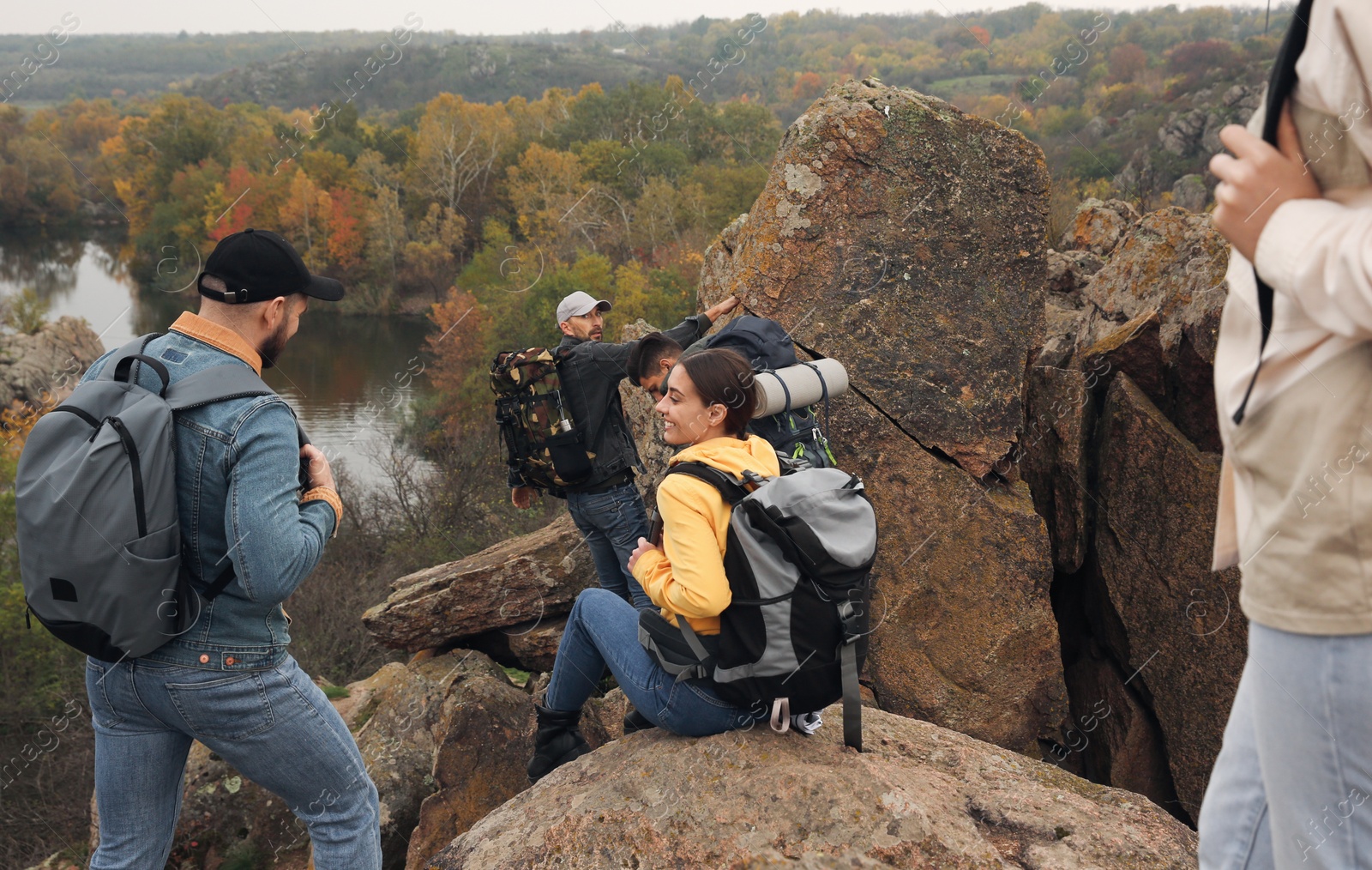 Photo of Group of hikers with backpacks climbing down mountain