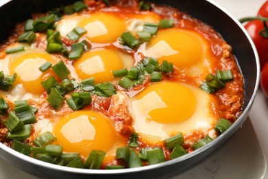 Photo of Delicious shakshuka in frying pan on table, closeup