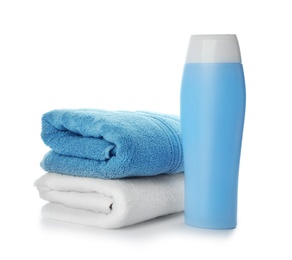Folded towels and shampoo isolated on white