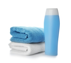 Photo of Folded towels and shampoo isolated on white