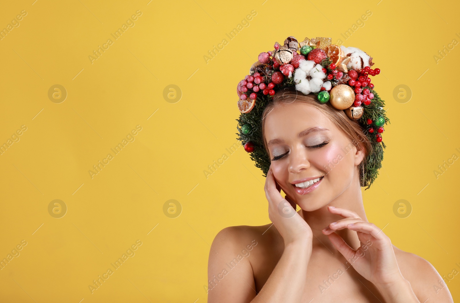 Photo of Beautiful young woman wearing Christmas wreath on yellow background. Space for text