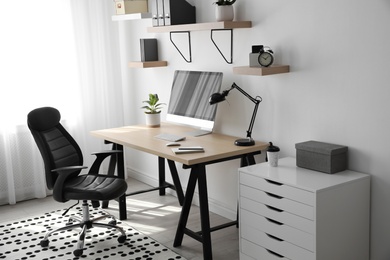 Photo of Comfortable office chair near table with modern computer