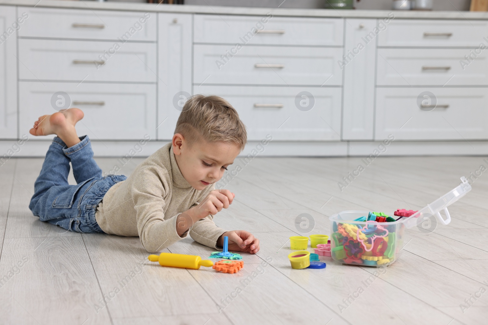 Photo of Cute little boy playing on warm floor in kitchen, space for text. Heating system