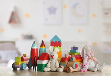 Set of different cute toys on wooden table in children's room