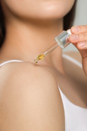 Photo of Woman applying essential oil onto shoulder, closeup