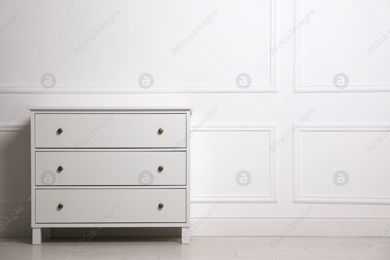 Photo of Stylish chest of drawers near white wall indoors, space for text