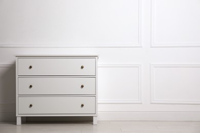 Stylish chest of drawers near white wall indoors, space for text
