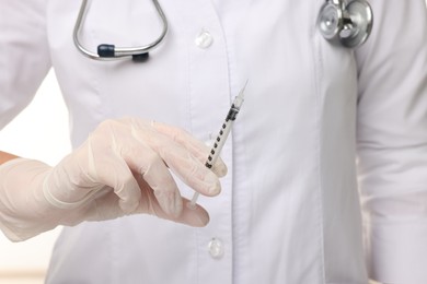 Doctor holding medical syringe on white background, closeup