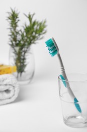 Photo of Light blue toothbrush in glass holder on white background