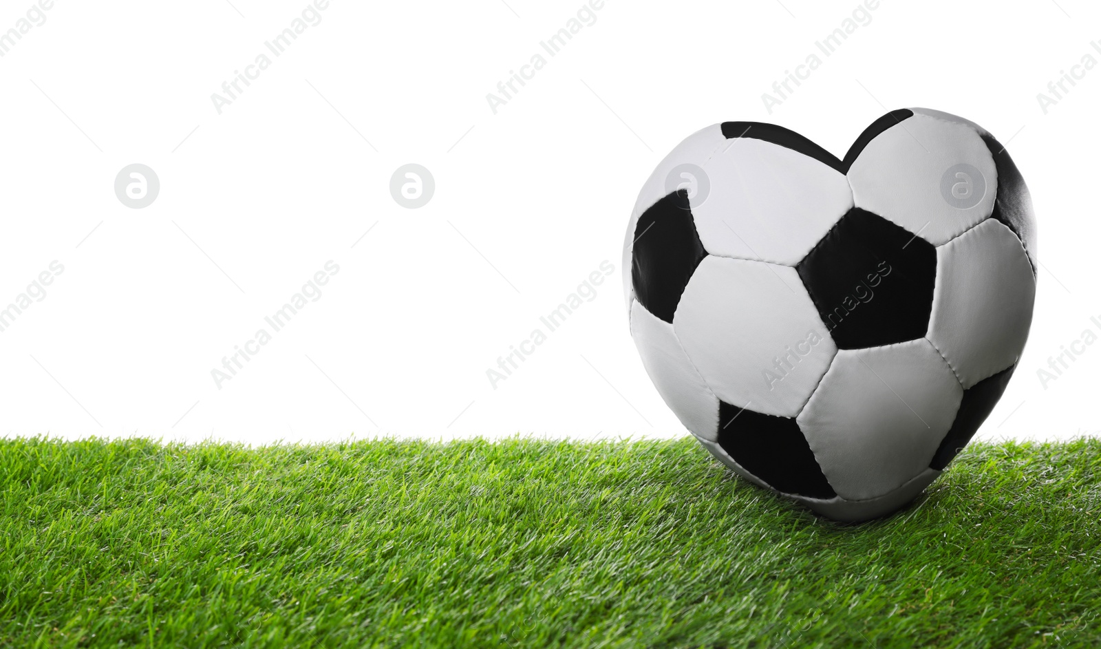 Image of Heart shaped soccer ball on green grass against white background. Space for text