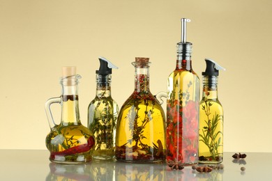 Photo of Cooking oil with different spices and herbs in bottles on beige table