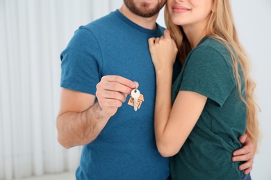 Young couple with key from their new house indoors, closeup