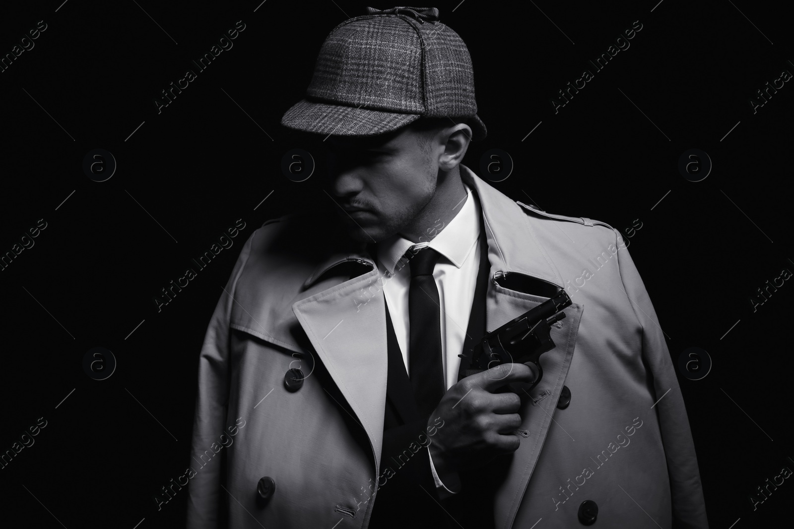 Photo of Old fashioned detective with revolver on dark background, black and white effect