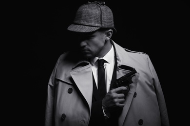 Photo of Old fashioned detective with revolver on dark background, black and white effect