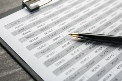 Photo of Clipboard with accounting document and pen on table, closeup