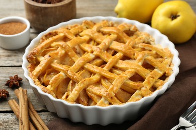 Photo of Tasty homemade quince pie with fresh fruits and spices on wooden table, closeup