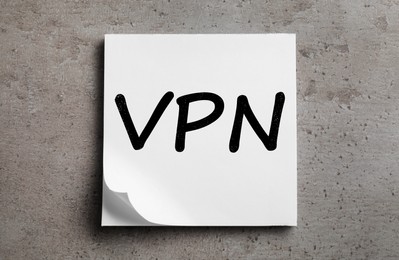 Photo of Paper sheet with acronym VPN (Virtual Private Network) on grey table, top view