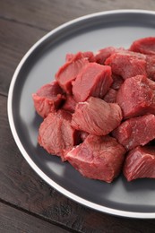 Photo of Pieces of raw beef meat on wooden table, closeup